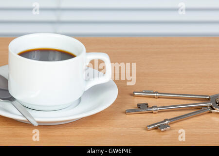 Tasse de café noir avec une cuillère et une soucoupe sur une table en bois avec un ensemble d'anciennes clés Banque D'Images