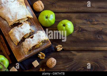 Des strudel aux pommes avec des pommes, raisins et noix, délicieuse pâtisserie végétarien sur planche de bois rustique with copy space Banque D'Images