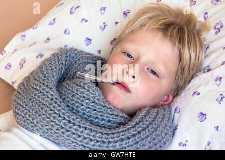 Sick little boy holding pose thermomètre au lit avec visage triste - santé et médecine concept Banque D'Images