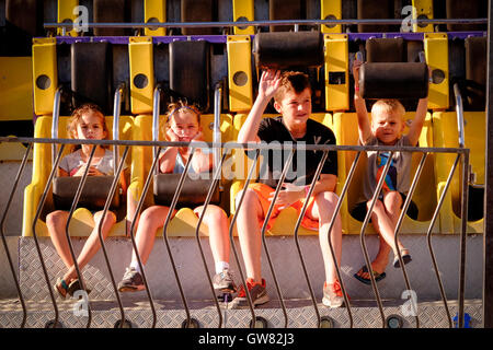 Quatre enfants attendent le début d'une ride sideshow à un country fair Banque D'Images