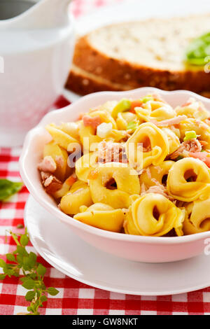 Libre d'un bol en céramique avec une salade de pâtes tortellini avec sur un set de table avec une nappe à carreaux rouges et blancs Banque D'Images