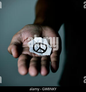 Libre d'un jeune homme avec un morceau de papier avec un symbole dessiné dans la paix, dans la paume de sa main Banque D'Images