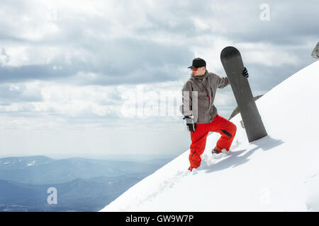 L'homme se dresse sur la pente snowboarder Banque D'Images