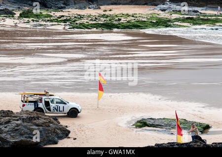 Regarder les nageurs sauveteurs entre rouge et jaune drapeaux de sécurité sur la plage de la baie de Treyarnon à Cornwall. Banque D'Images