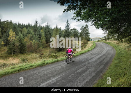 Deux femmes cresting cycliste une colline dans le Lake District, Cumbria, Royaume-Uni. Banque D'Images