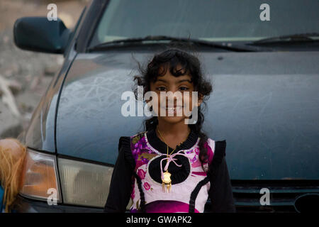 Sur, Oman, le 22 octobre 2013 : Little girl omanais debout sur une voiture, en me regardant dans l'appareil photo Banque D'Images