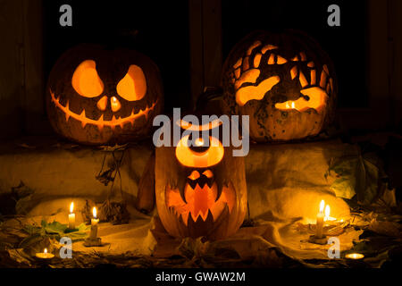 Composition Photo de trois citrouilles à l'Halloween. Jack, les mains, les terribles et un cyclope de la citrouille à l'encontre d'une vieille fenêtre, feuilles Banque D'Images