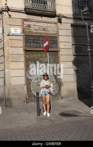 Une jeune femme debout sur une rue de Barcelone à l'aide de son téléphone. Banque D'Images