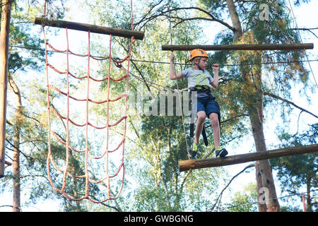 Portrait de brave garçon active bénéficiant d'escalade en sortie au parc aventure sur tree top Banque D'Images