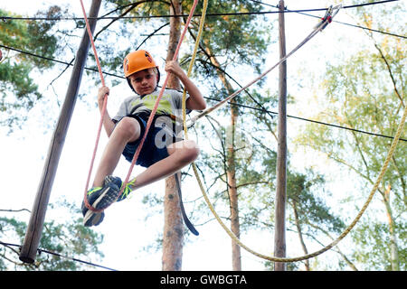 Portrait de brave garçon active bénéficiant d'escalade en sortie au parc aventure sur tree top Banque D'Images