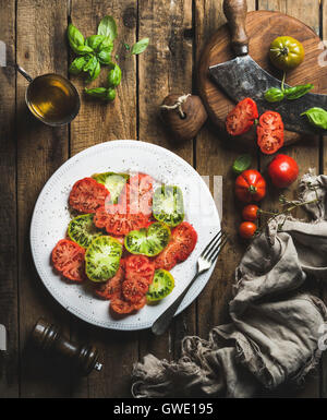 Heirloom salade de tomates à l'huile d'olive et basilic plus vieux rustique en arrière-plan, Vue de dessus, la composition verticale Banque D'Images