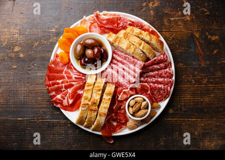 La viande froide plaque avec prosciutto, salami, pain ciabatta olives et sur fond de bois Banque D'Images