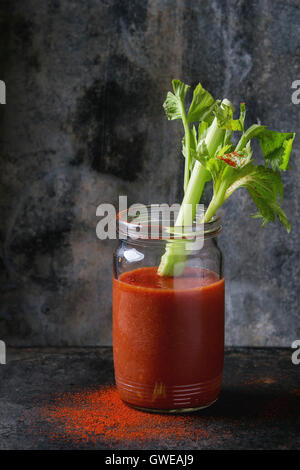 Pot en verre de jus de tomate et le paprika rouge, servi avec branche de céleri et le paprika en poudre sur fond dark iron. Manger sain Banque D'Images