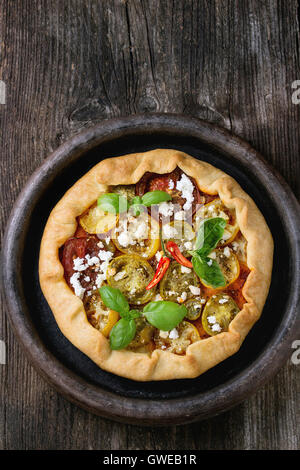 Tarte aux légumes maison ouvrir avec galette tomates colorées, tomates séchées, feta et basilic frais, servis dans le bac d'argile sur Banque D'Images