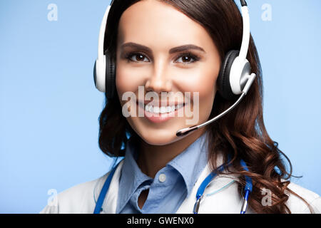 Portrait of happy smiling young doctor in casque, sur fond bleu lumineux Banque D'Images
