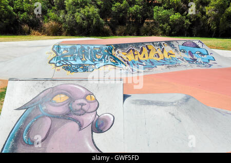 Spearwood Skate Park avec des rampes en béton et l'art urbain dans le cadre d'arbres sous un ciel bleu à Spearwood, Australie occidentale Banque D'Images