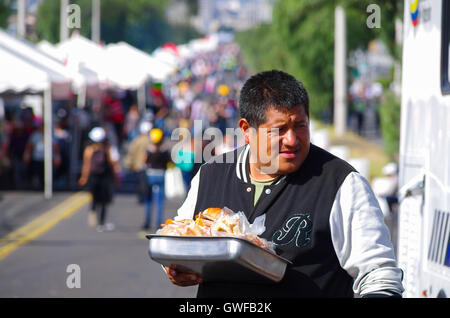 Quito, Équateur - Juillet 07, 2015 : homme non identifié dans la vente de sandwichs le Pape François masse. L'alimentation de rue est habituellement fait maison et contribue à fournir un revenu supplémentaire aux familles de la classe basse Banque D'Images