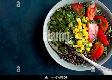 Poblano rôtis le quinoa garni de tomates, de maïs et de coriandre. Photographié en vue de dessus sur un fond bleu foncé. Banque D'Images