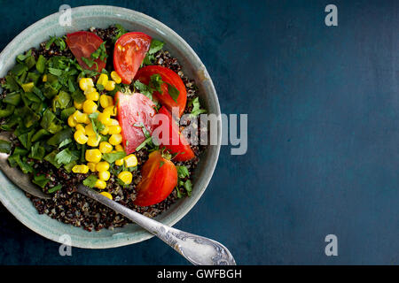 Poblano rôtis le quinoa garni de tomates, de maïs et de coriandre. Photographié en vue de dessus sur un fond bleu foncé. Banque D'Images