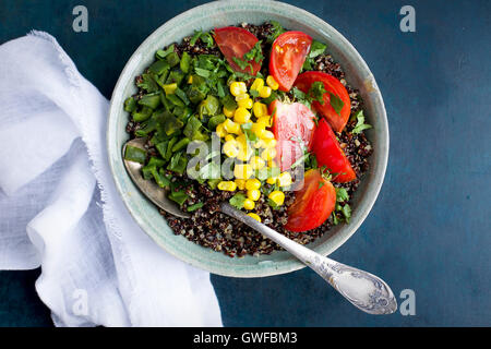 Poblano rôtis le quinoa garni de tomates, de maïs et de coriandre. Photographié en vue de dessus sur un fond bleu foncé. Banque D'Images