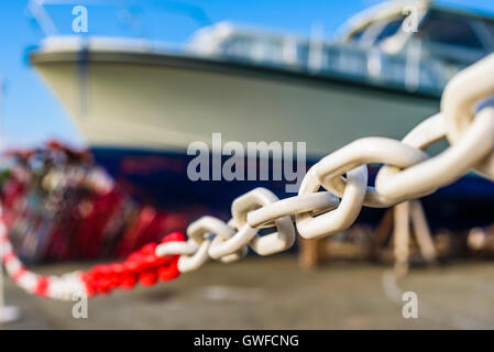 Focalisation étroite sur la chaîne en plastique blanc et rouge avec un grand bateau à moteur floue en arrière-plan. Banque D'Images