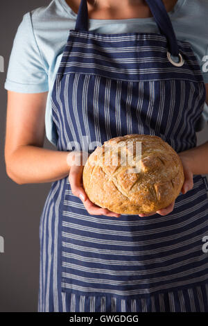 Woman Wearing Apron Holding miche de pain fraîchement cuit au four Banque D'Images