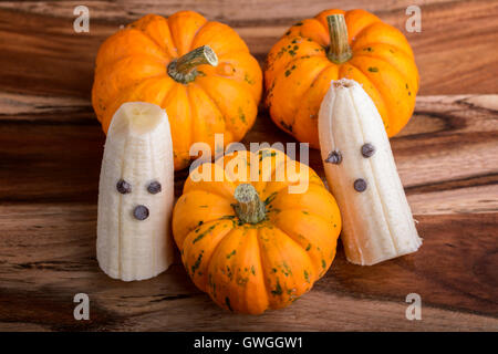 Trois citrouilles et fantômes faits avec banane et chocolat pour l'halloween sur du bois Banque D'Images