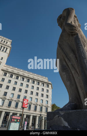 L'une des nombreuses statues qui ornent la Placa de Catalunya, Barcelone. Fontaine Métro Orange sign dans la distance. Banque D'Images
