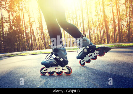 Adolescente sur patins à à l'été. Image sport des patins. Banque D'Images