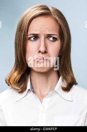 Jeune femme faisant la moue expression sur fond gris Banque D'Images