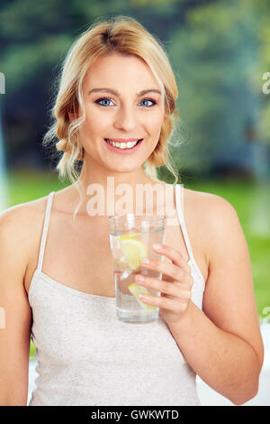 Fille de boire dans un verre d'eau glacée au citron Banque D'Images