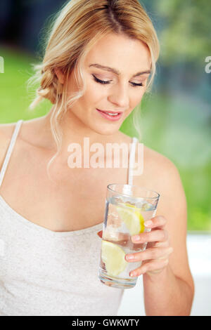 Fille de boire dans un verre d'eau glacée au citron Banque D'Images