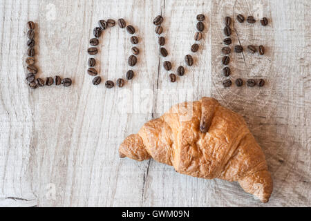 Croissant sur fond de bois. titre amour les grains de café Banque D'Images