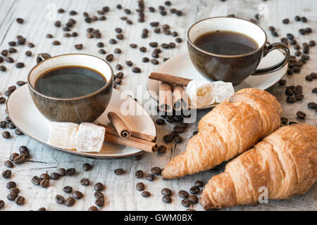 Tasse de café avec des grains, croissant sur fond de bois Banque D'Images