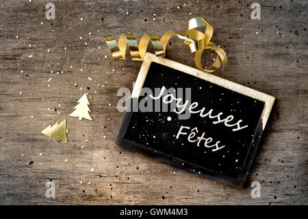 Peu de signes avec message joyeuses fêtes rédigé en français sur fond de bois Banque D'Images