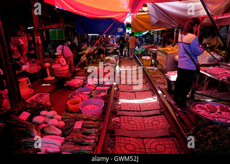 Vendeurs vendant de la nourriture au marché ferroviaire de Maeklong, également connu sous le nom de « marché de pulldown parapluie » ou Talat ROM Hup., situé sur un ensemble de voies ferrées qui traversent directement la zone du marché où les vendeurs ajustent rapidement leurs stands et auvents rétractables pour permettre au train de passer, puis reprendre rapidement leurs activités comme si rien ne s'était passé, situé à Samut Songkhram, à environ 37 miles à l'ouest de Bangkok, en Thaïlande Banque D'Images