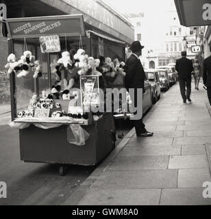 Années 1950, tableau historique du centre de Londres d'un doudou et souvenir, rue commerçant debout près de son échoppe en attente pour les entreprises. Banque D'Images