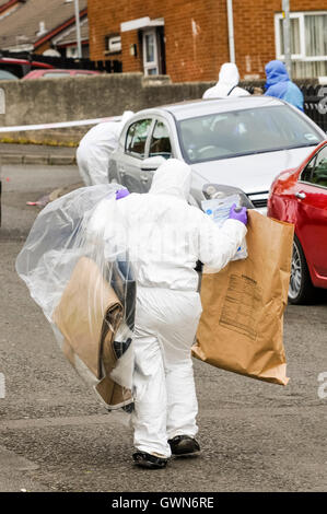 Belfast, Irlande du Nord. 30 mai 2015 - Une police judiciaire SOCO vêtue d'un costume blanc de chaudière transporte des sacs de preuve loin d'une scène de crime Banque D'Images