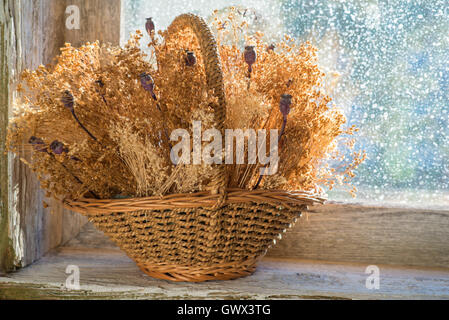 Panier de fleurs séchées sur le rebord d'une vieille fenêtre en bois Banque D'Images