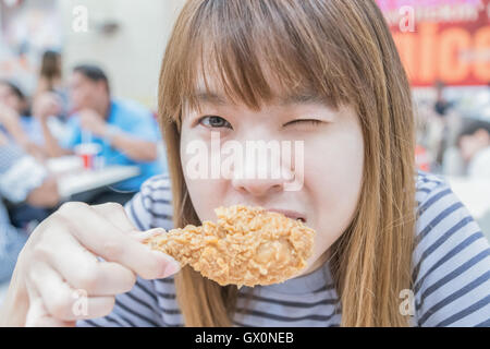 Young happy woman holding et de manger du poulet frites Banque D'Images