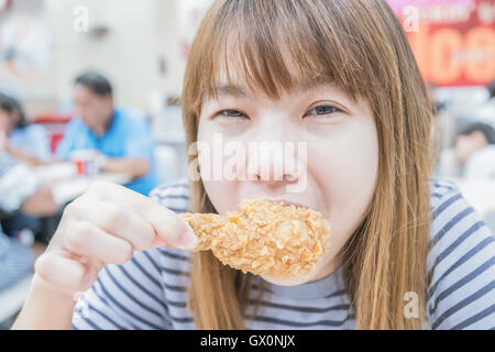 Young happy woman holding et de manger du poulet frites Banque D'Images