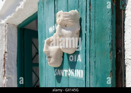 Masques en porcelaine à vendre à Oia, Santorin contre une porte en bois vert. Banque D'Images