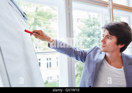 Jeune homme avec stylo à présentation avec tableau blanc Banque D'Images