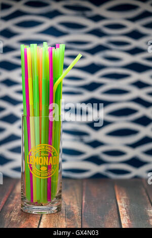 Pailles multicolores dans un verre de limonade sur la surface du bois Banque D'Images