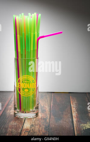 Pailles multicolores dans un verre de limonade sur la surface du bois Banque D'Images