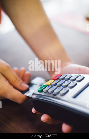 Insère la main de femme dans le terminal de carte de crédit Banque D'Images