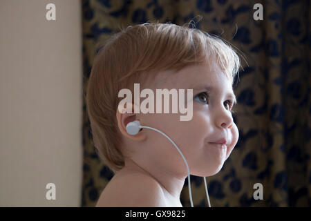 Clouse-up portrait beau happy baby avec des écouteurs pour écouter de la musique. l'horizontale Banque D'Images