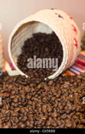Close up of Brown café en grains en versant de l'osier blanc bol Banque D'Images