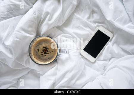 Tasse de café et du smartphone sur le lit, vue d'en haut Banque D'Images