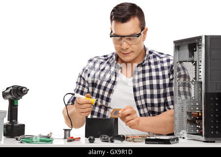 Technicien en informatique travaillant avec un fer à souder et la réparation d'un ordinateur isolé sur fond blanc Banque D'Images